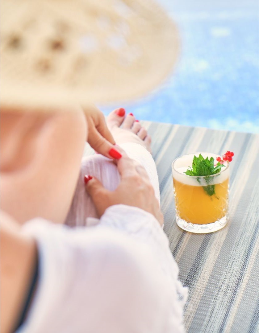 Woman sitting by the pool with a beverage next to her